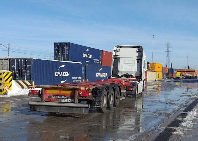Un camión transporta un contenedor en una terminal ferroviaria.
